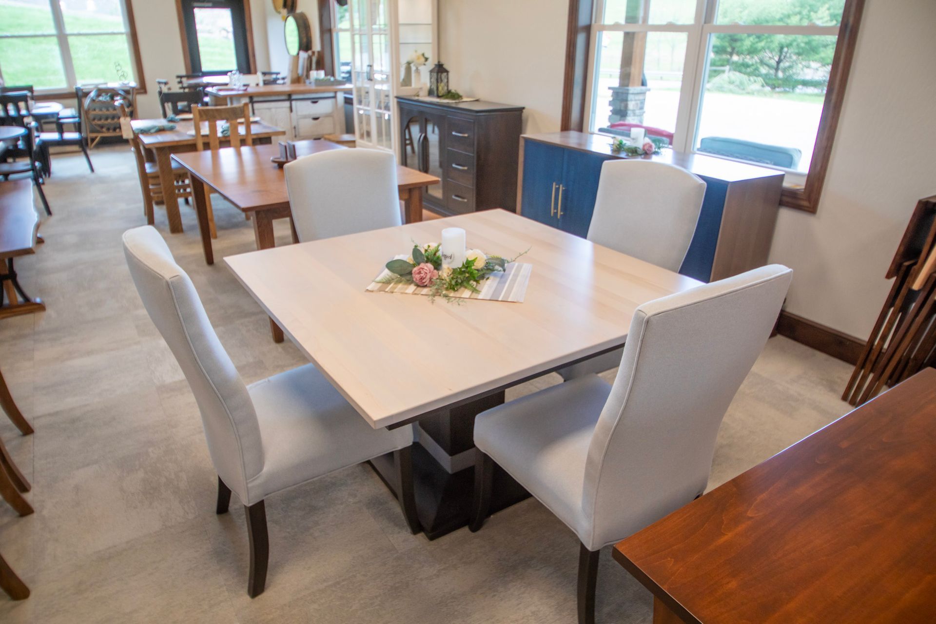 A dining room set with a square table and four upholstered chairs.