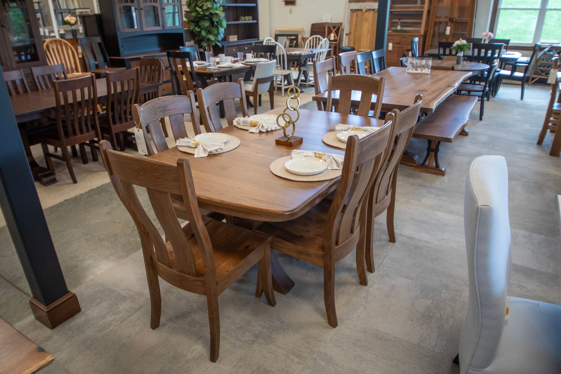 A showroom with various wooden dining tables and chairs, some set for dining.