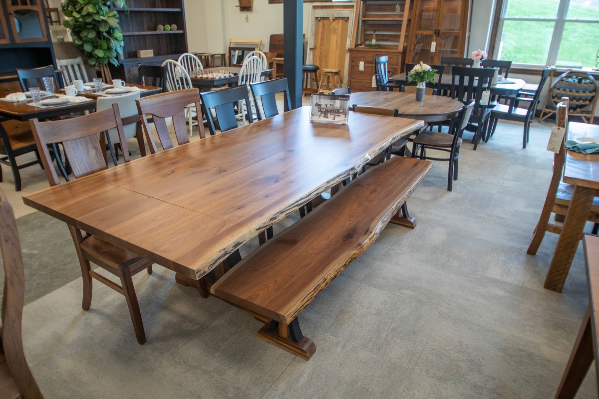Wooden dining table with bench and chairs in a showroom.