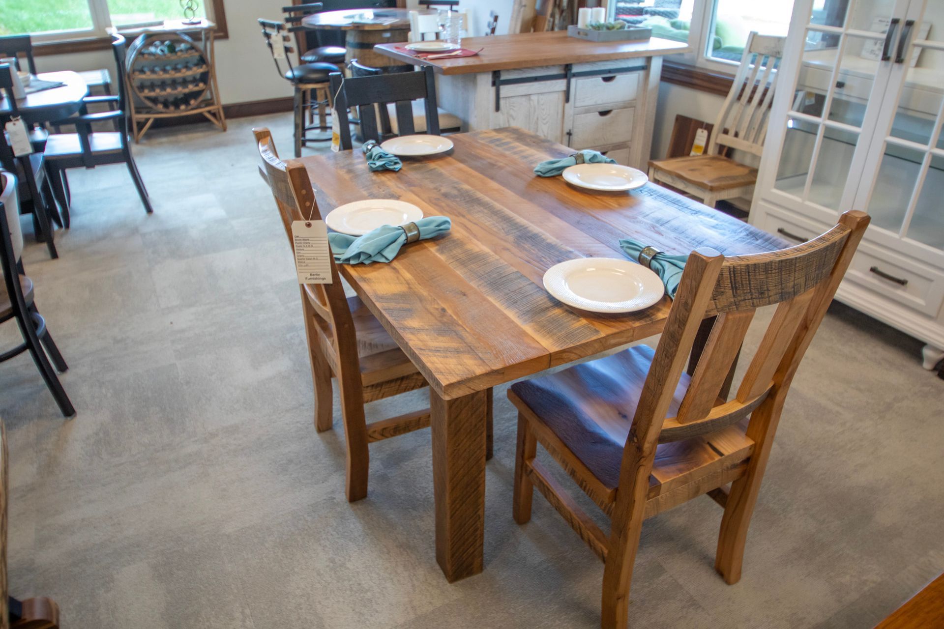 Rustic wooden dining table with four chairs set for a meal in a brightly lit room.