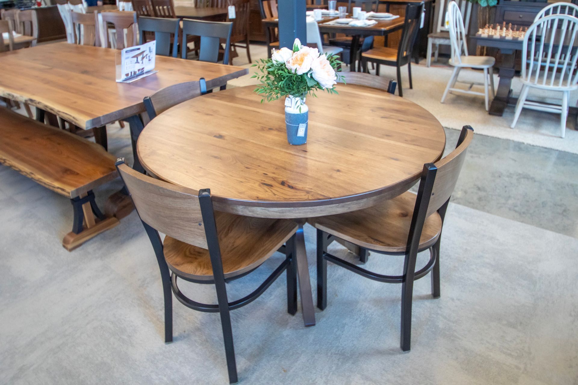 Round wooden table with three chairs, flowers, in a furniture store.
