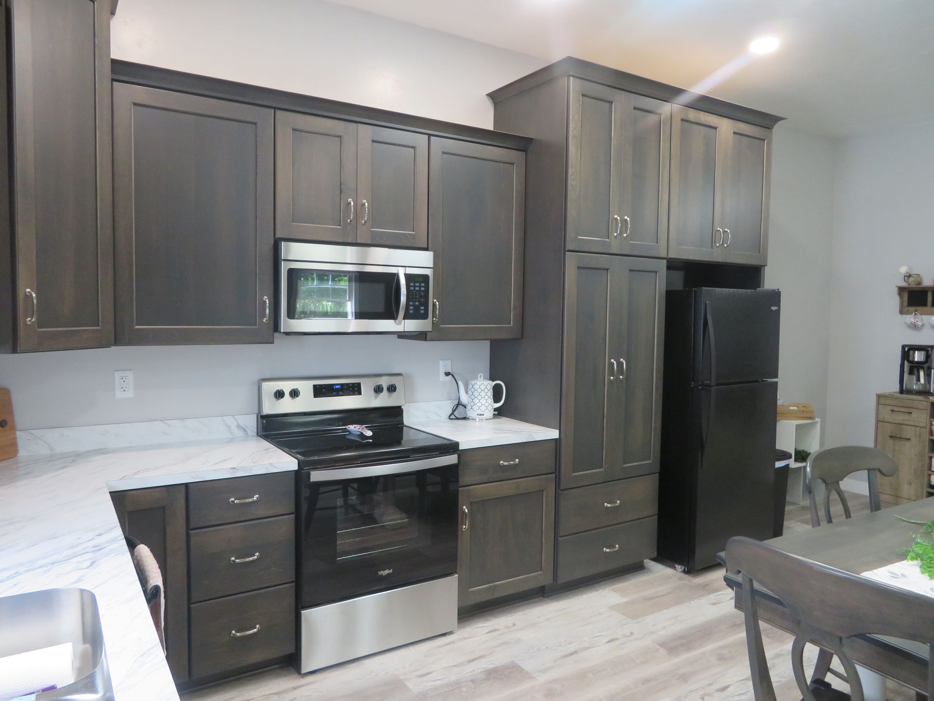 Kitchen with dark gray cabinets, stainless steel appliances, and white countertops.