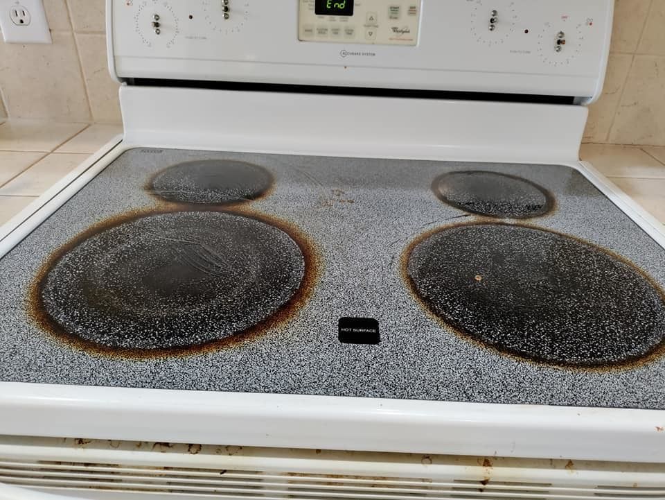 A white stove top with a dirty stove top