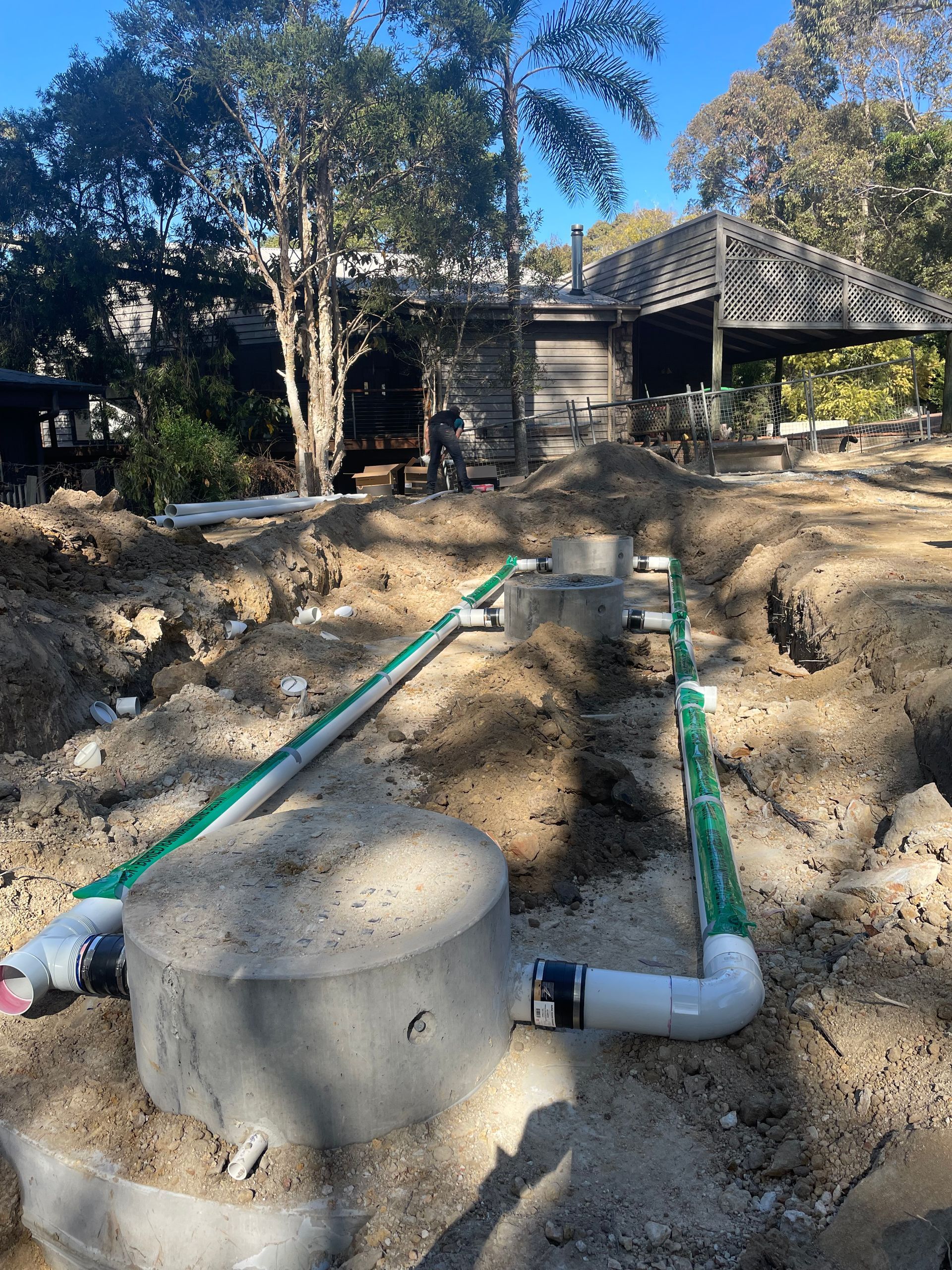 A septic system is being installed in the dirt in front of a house.