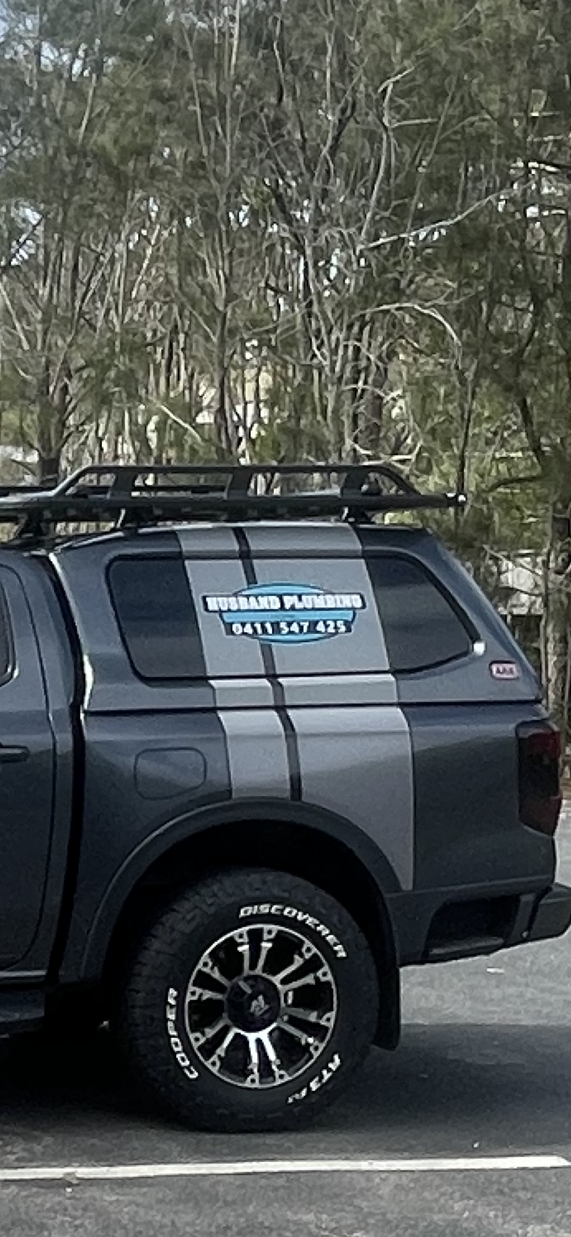 A black truck with a roof rack is parked in a parking lot.