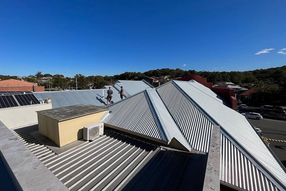 People Inspecting The Roof In Clear Sky Weather — Roofer in Lake Macquarie, NSW