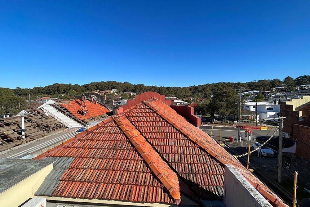 Roof repairs on older tiled home with tradespeople replacing damaged tiles and maintaining structure
