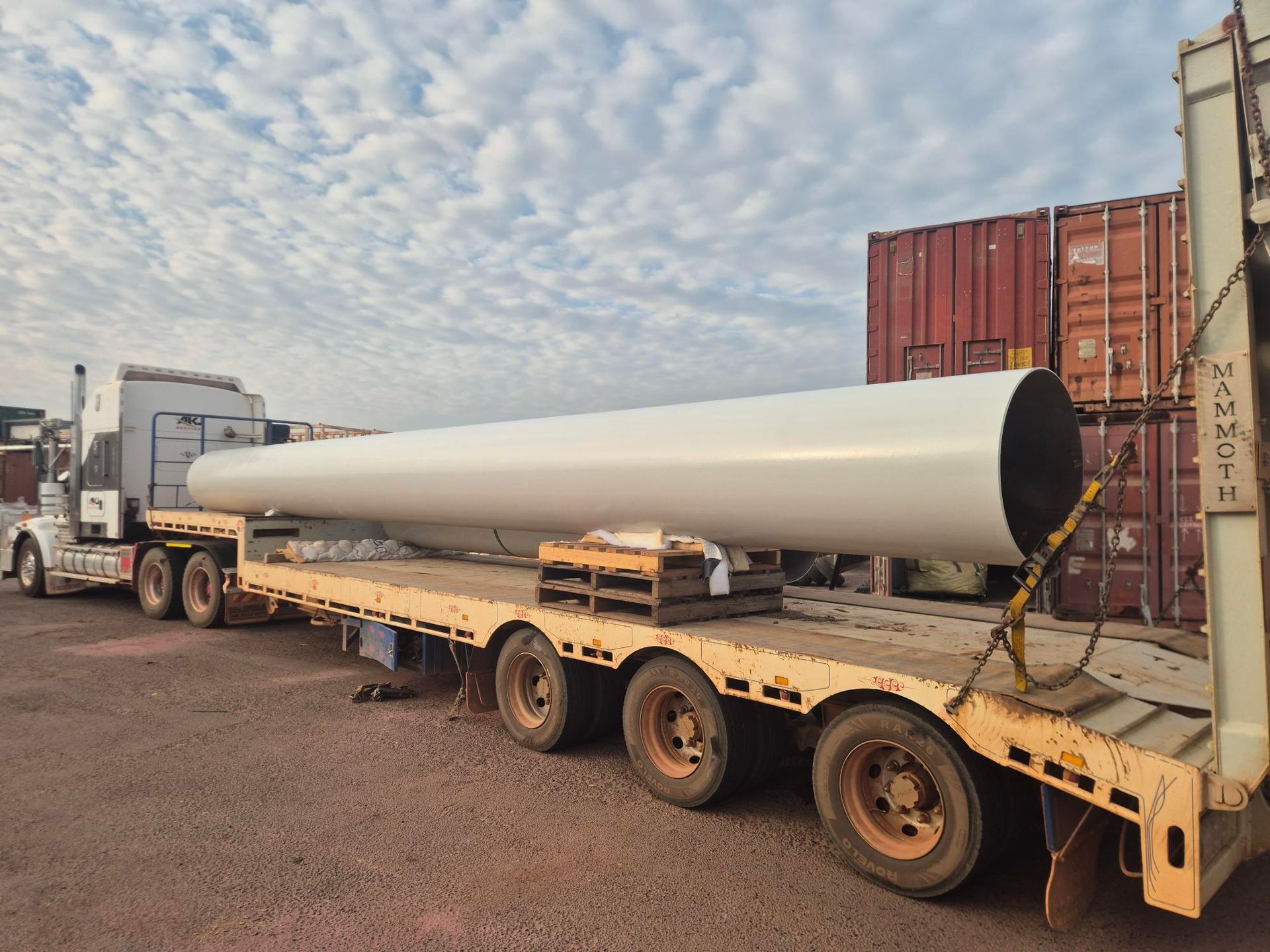 Long white wind turbine blade on a flatbed trailer in an industrial yard — Sirocco Industrial in Pinelands, NT