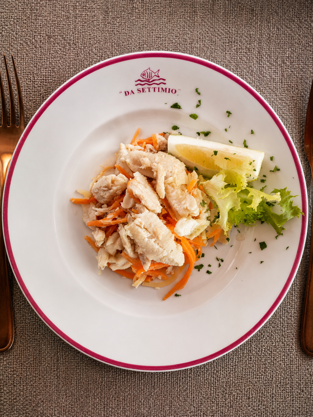 Piatto bianco con insalata di granchio, spicchio di limone e guarnizione di lattuga su una tovaglietta intrecciata.