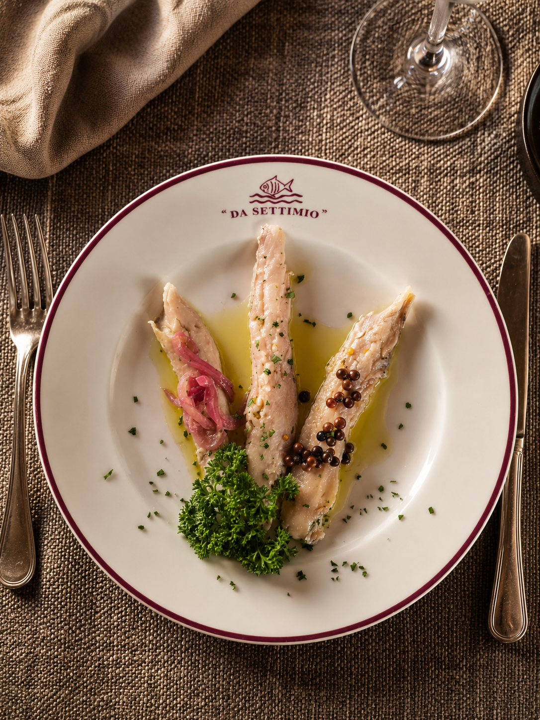 Elegante antipasto di frutti di mare con guarnizione verde su un piatto bianco, adagiato su una tovaglia dalla texture particolare.