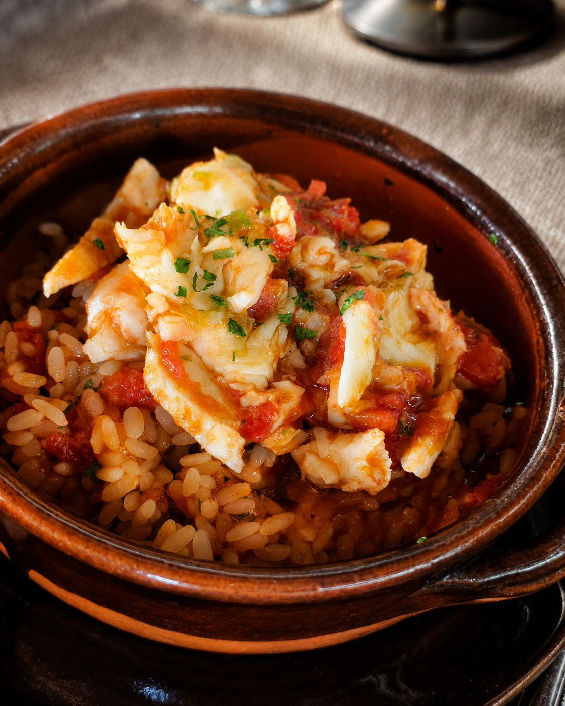 Ciotola di riso integrale condita con pesce sminuzzato ed erbe aromatiche, servita su un tavolo rustico.