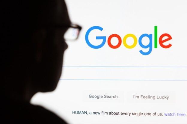 A man wearing glasses is looking at a google search page