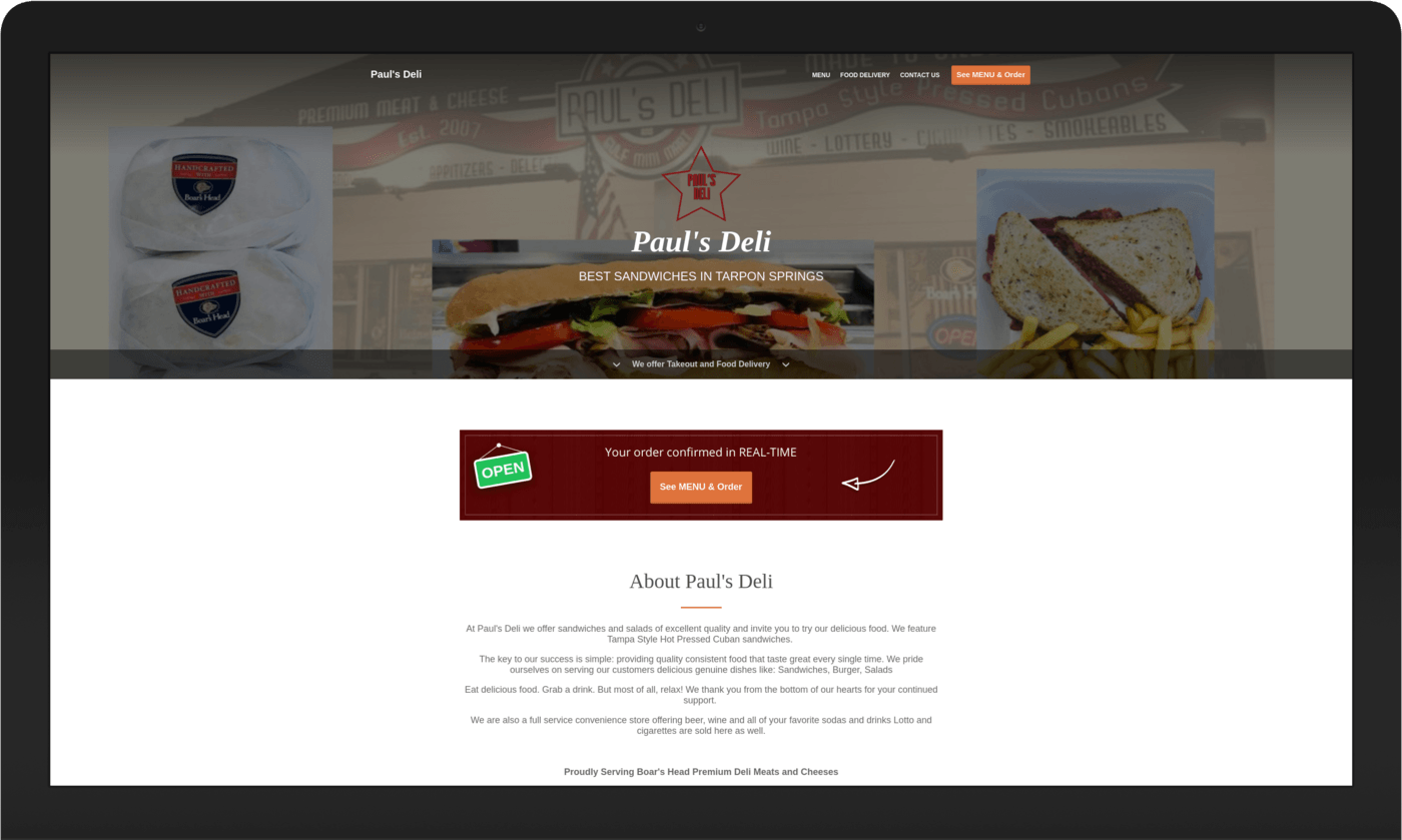 A laptop screen shows a website for a deli with a sandwich on it.