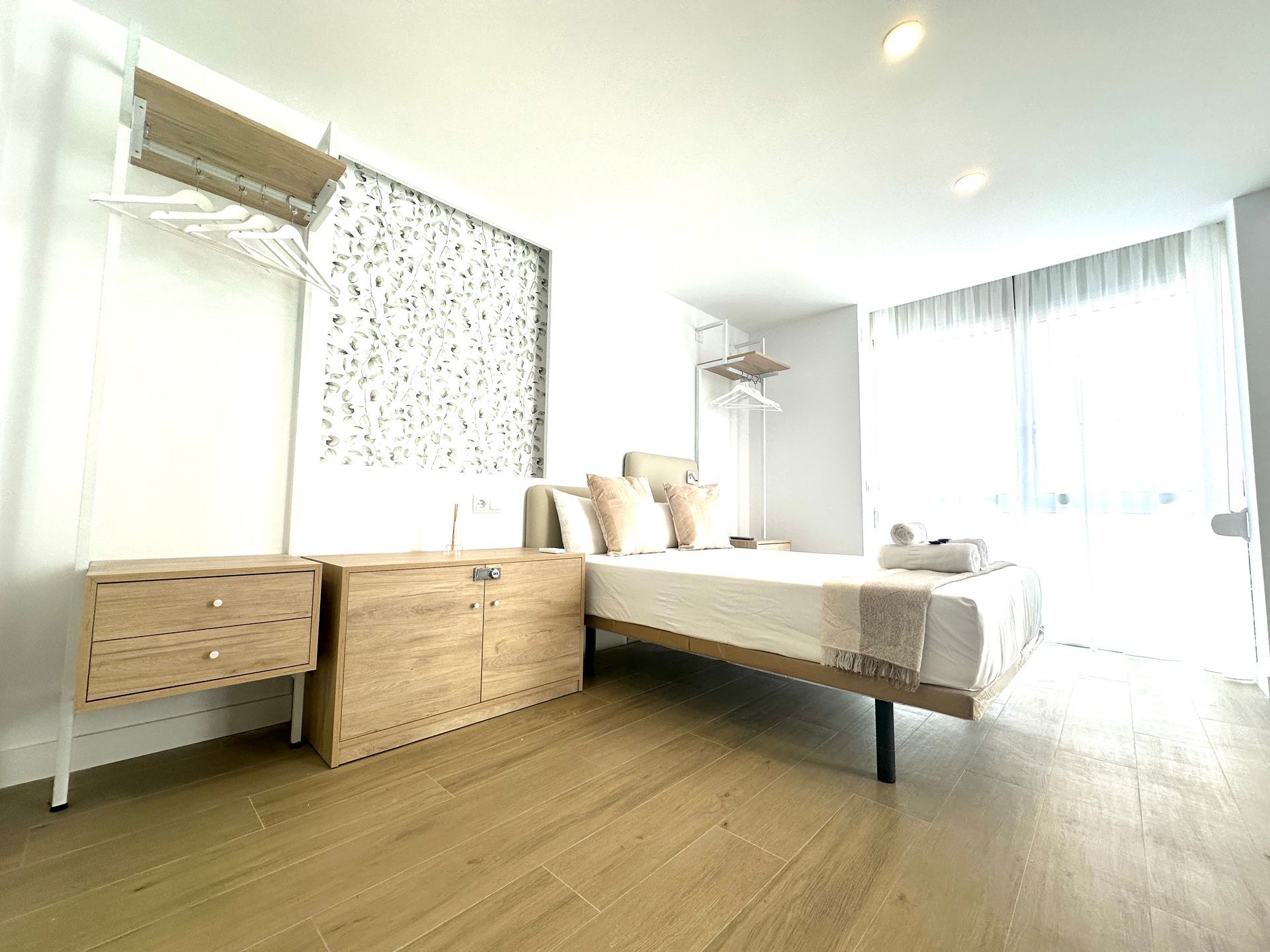 Un dormitorio con cama, cómoda, mesita de noche y ventana.