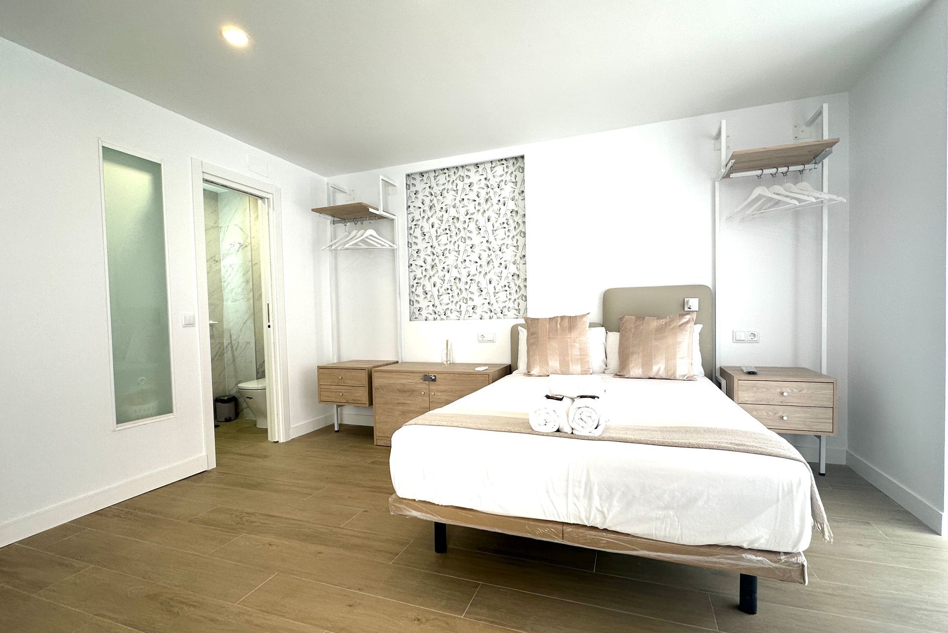 Un dormitorio con una cama, mesitas de noche y un baño.