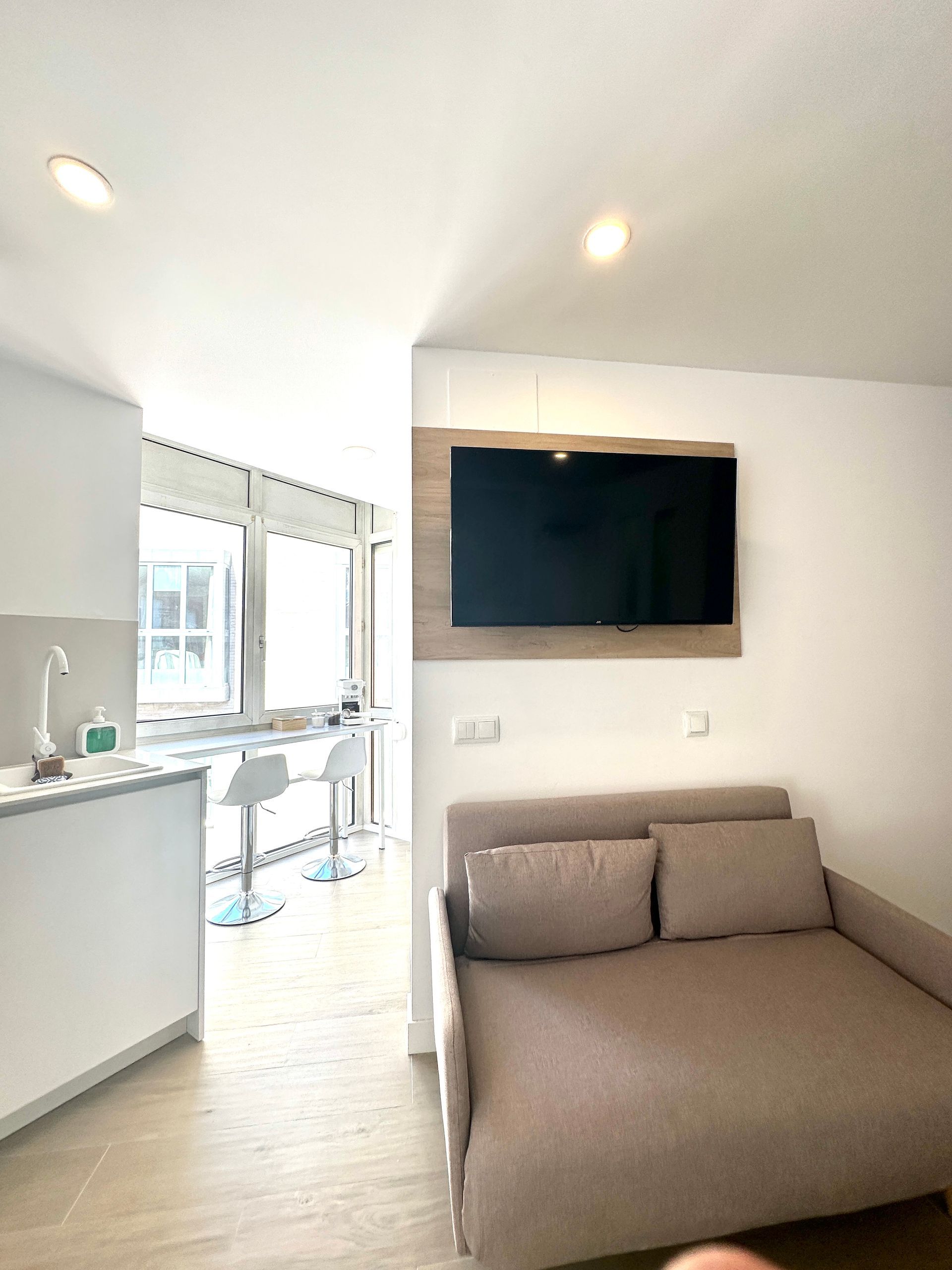 Una sala de estar con un sofá y un televisor de pantalla plana en la pared.