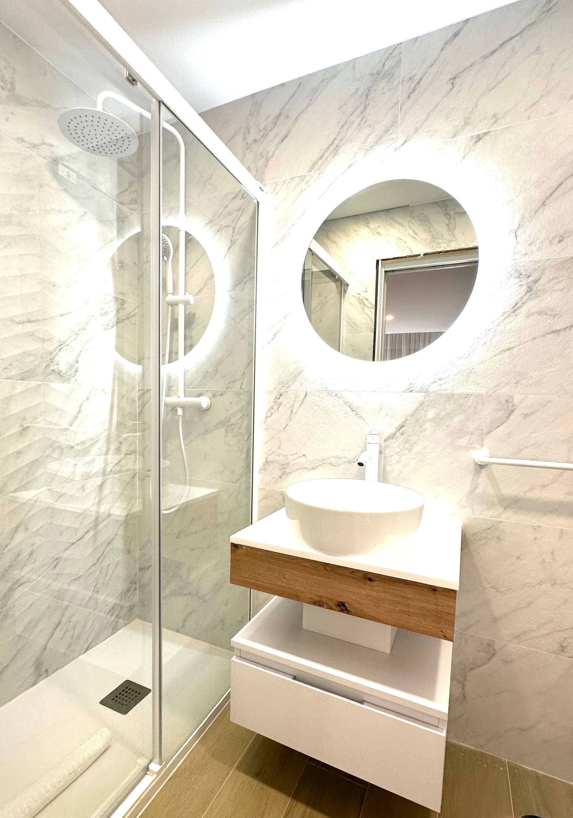 Un baño con lavabo, ducha y espejo.