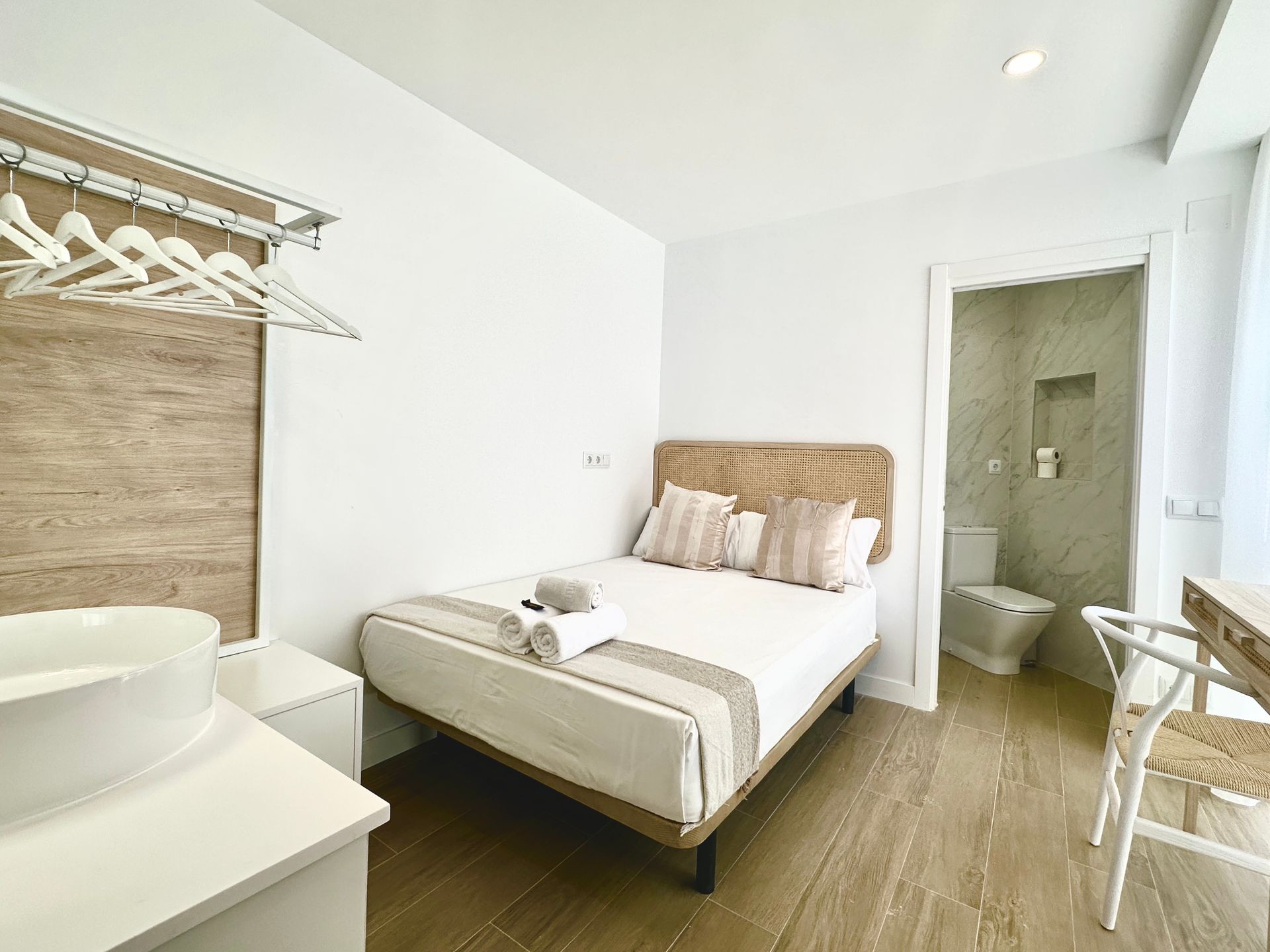 Un dormitorio con una cama, lavabo, silla e inodoro.