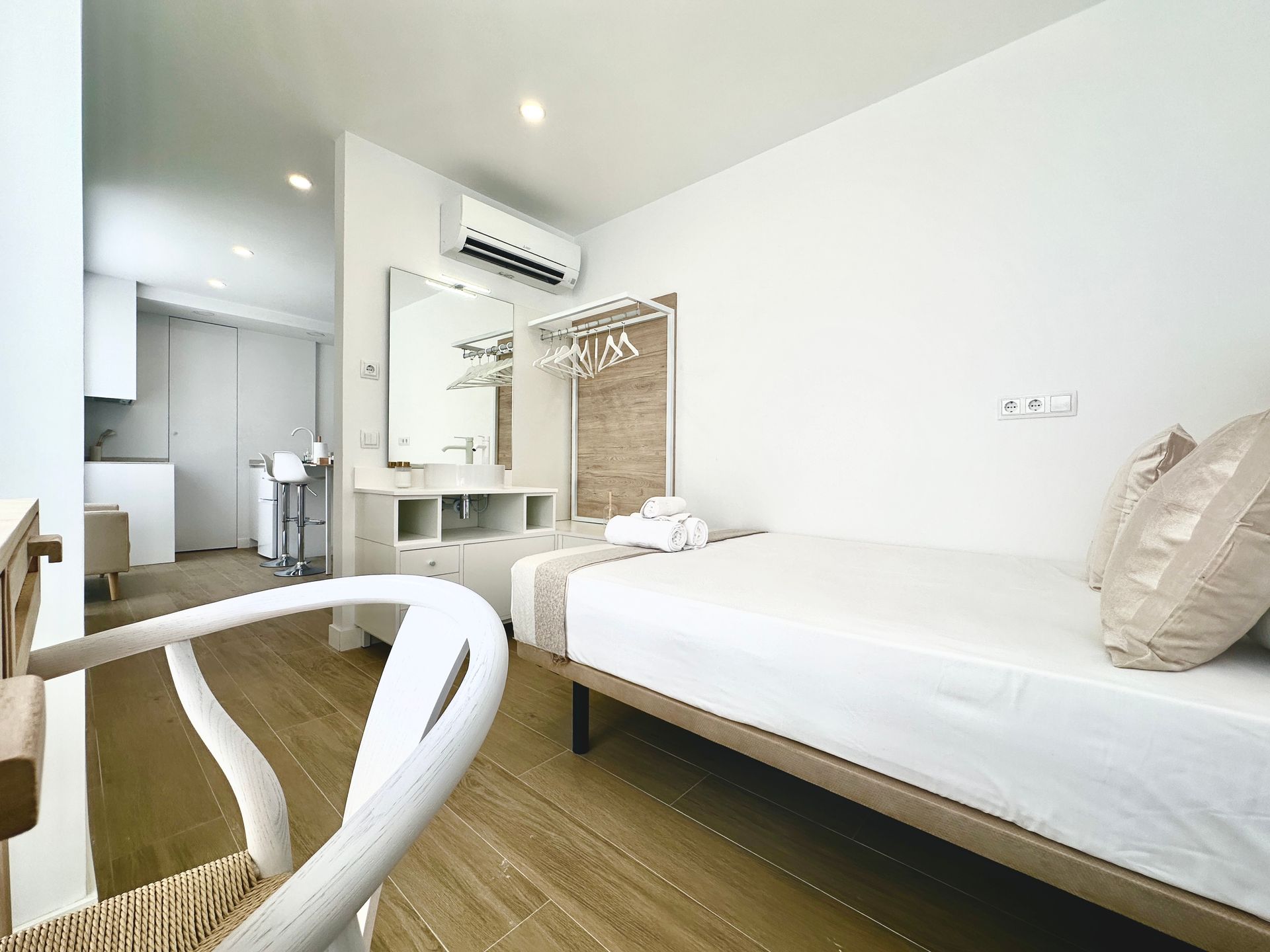 Un dormitorio con una cama, una silla y un espejo.