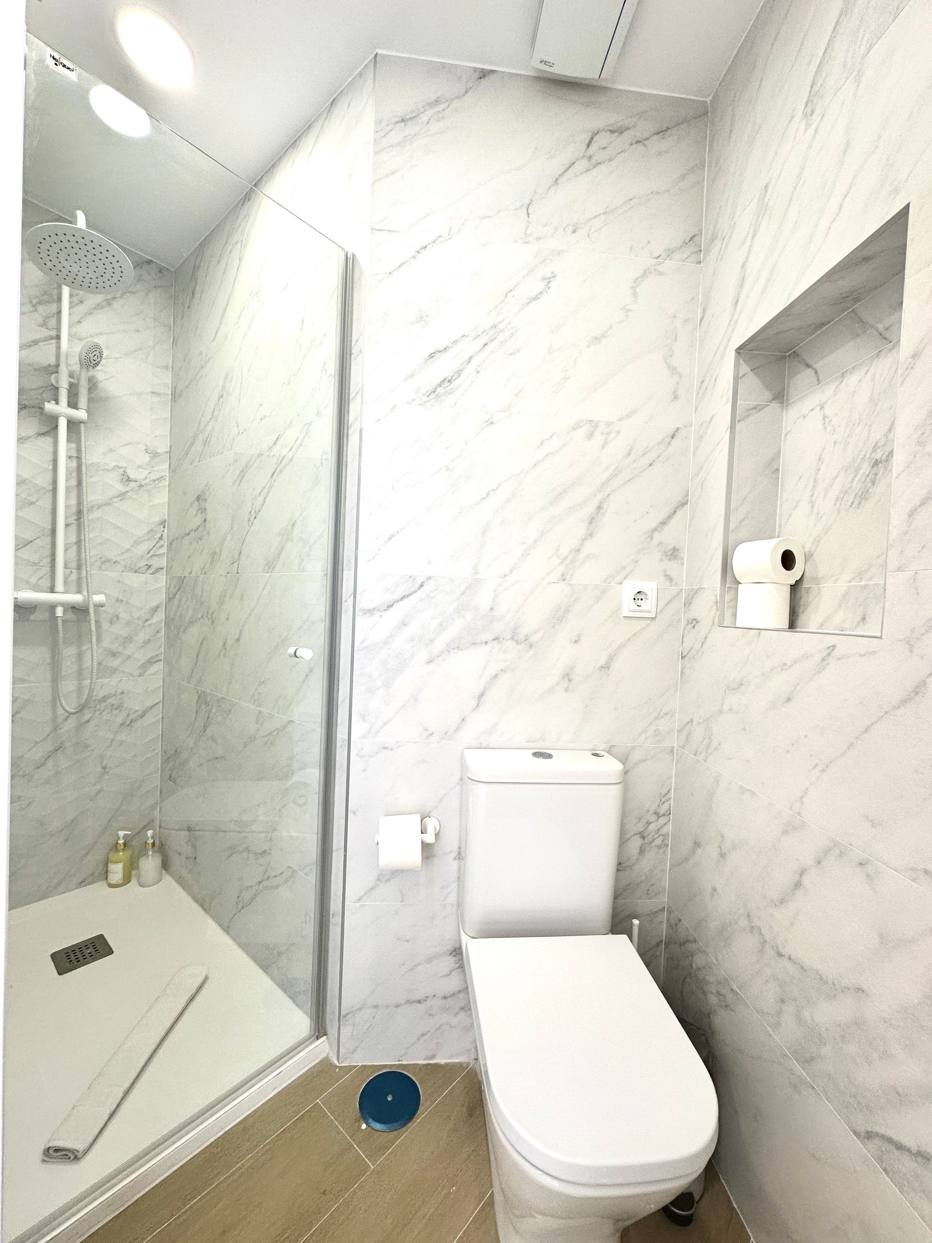 Un baño con inodoro, ducha y espejo.