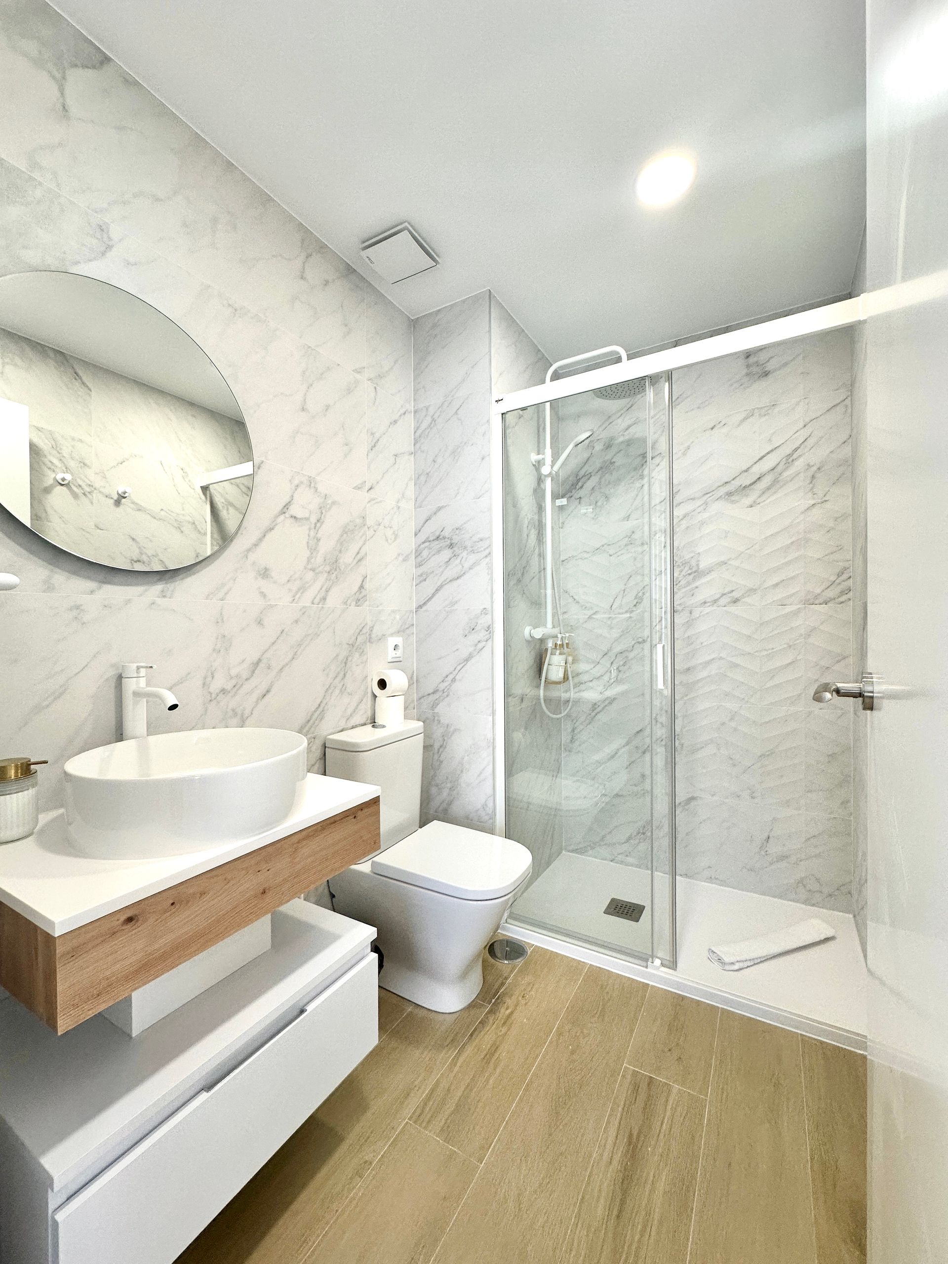 Un baño con lavabo, inodoro, ducha y espejo.