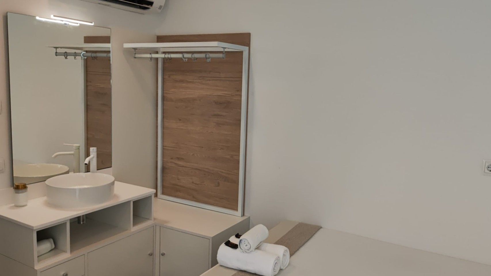 Un baño con lavabo, espejo, armarios y toallas.