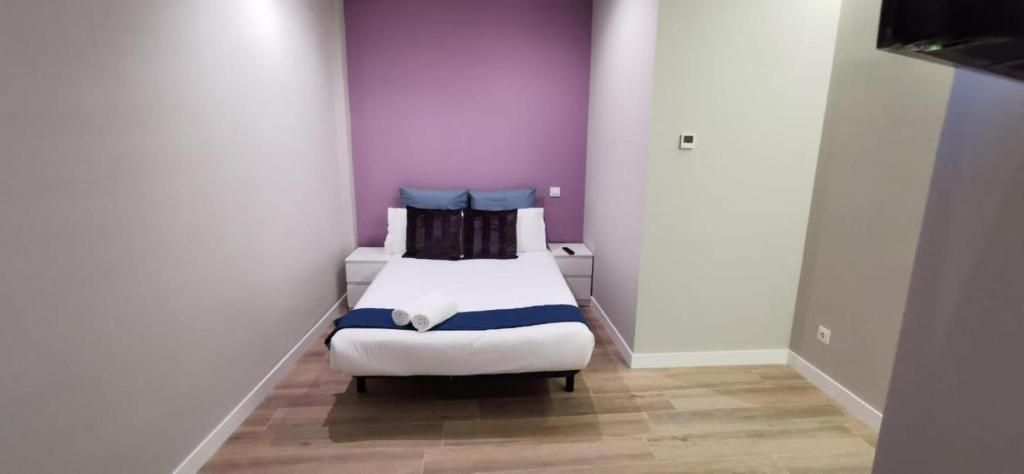 Un dormitorio pequeño con una cama y una pared morada.
