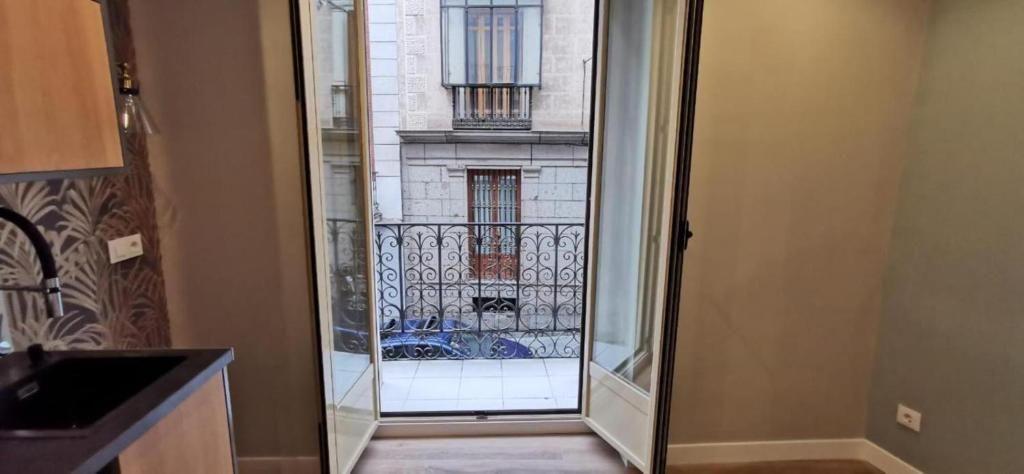 Una cocina con fregadero y un balcón con vista a un edificio.