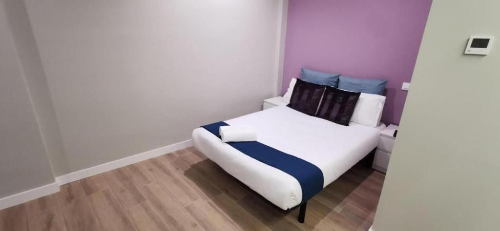 Un dormitorio con una cama y una pared morada.