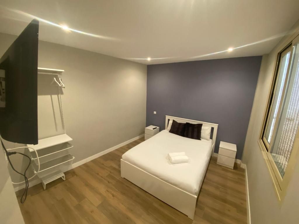 Un dormitorio con una cama, mesitas de noche, un televisor y una ventana.
