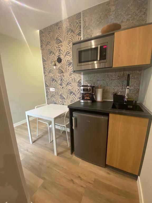 Una pequeña cocina con mesa y sillas y un microondas.