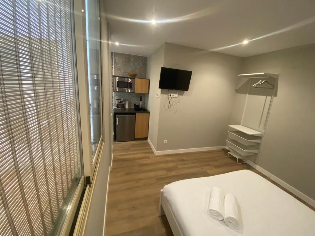 Un dormitorio con cama, televisión y cocina.