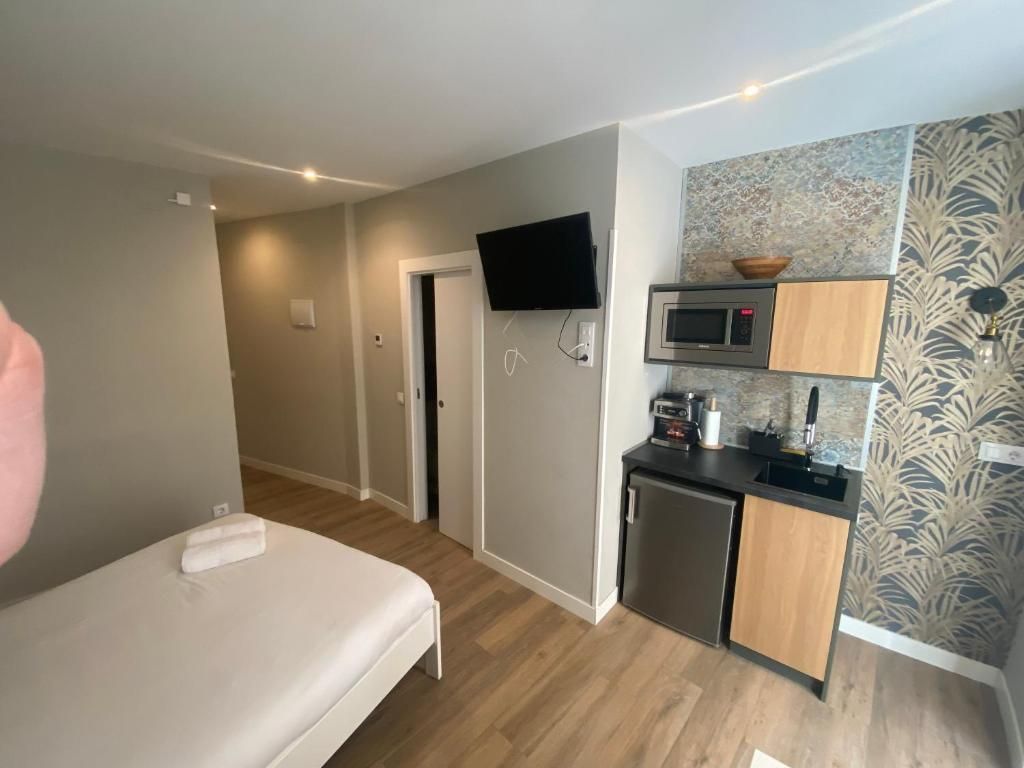 Un dormitorio con cama, televisión, microondas y fregadero.