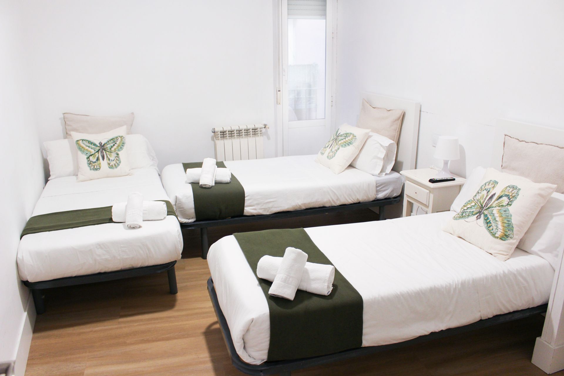 Un dormitorio con tres camas y una mesita de noche.