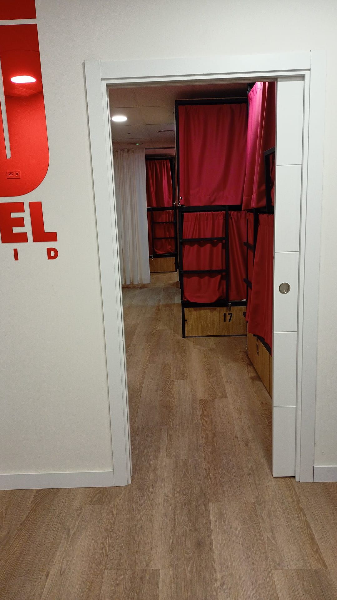 Una puerta que conduce a una habitación con literas y cortinas rojas.