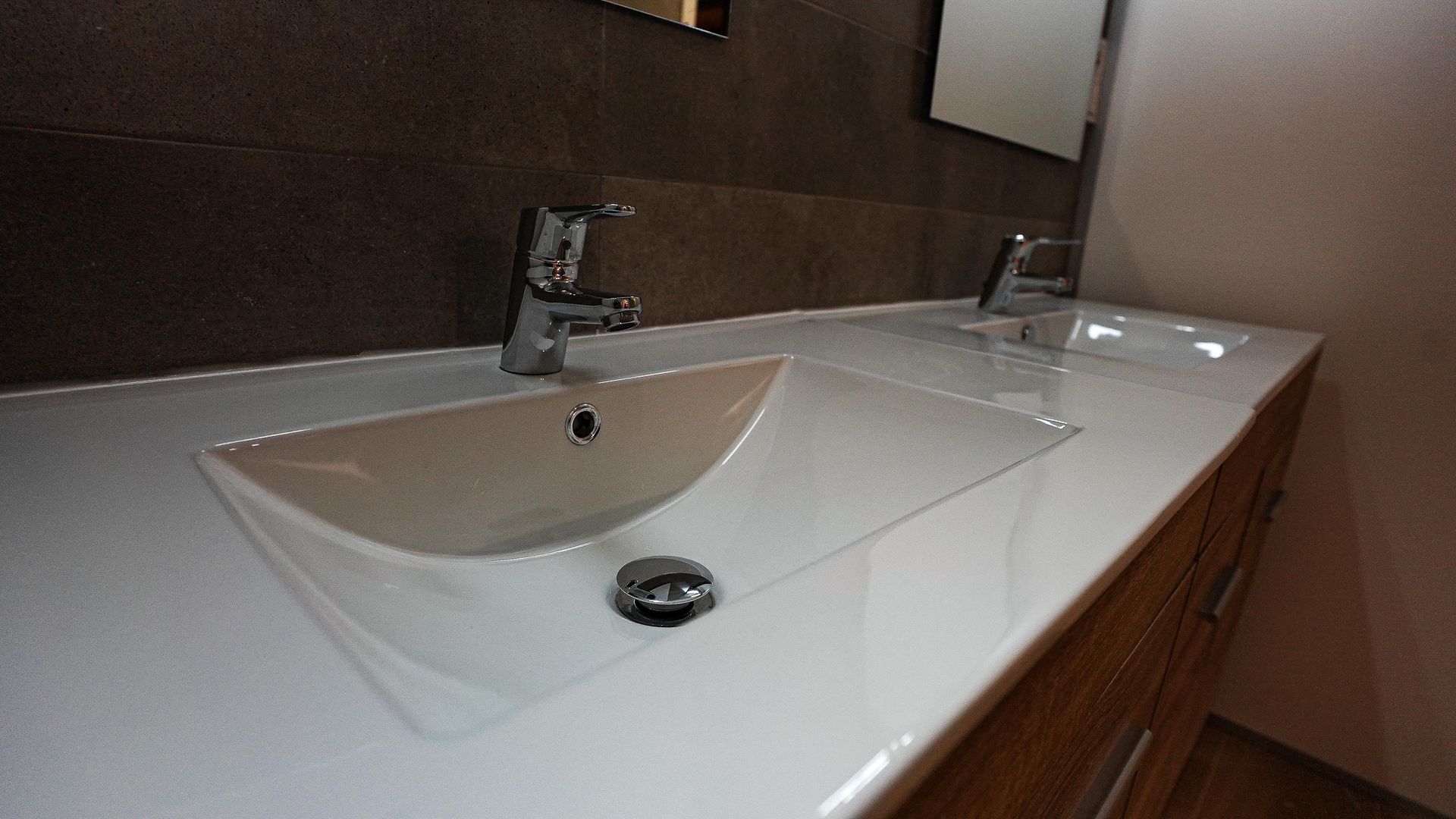 Un lavabo de baño con dos grifos y un espejo.