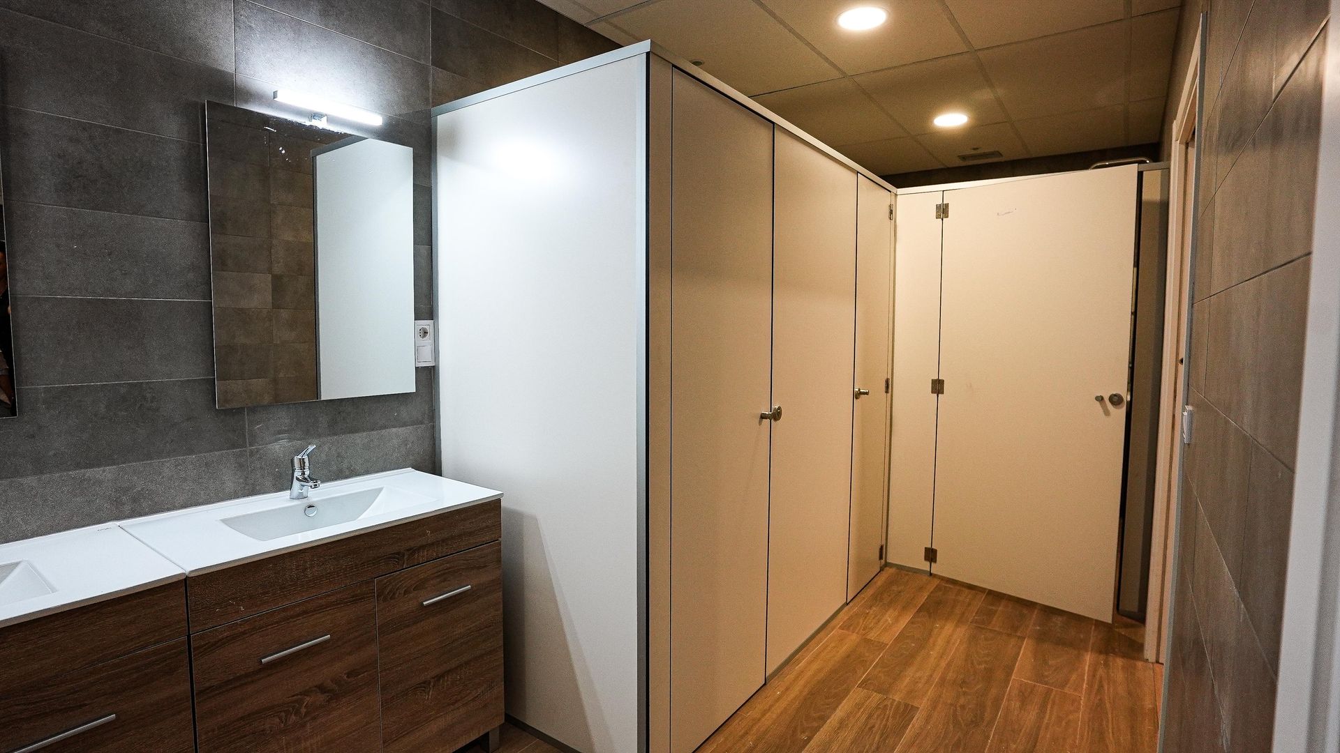 Un baño con lavabo, espejo y suelo de madera.