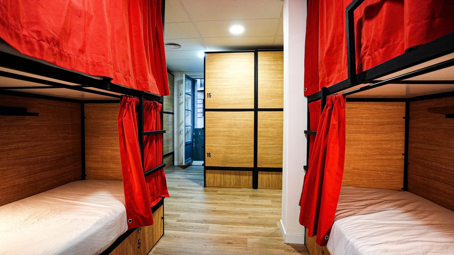 Una habitación con cuatro literas y cortinas rojas.