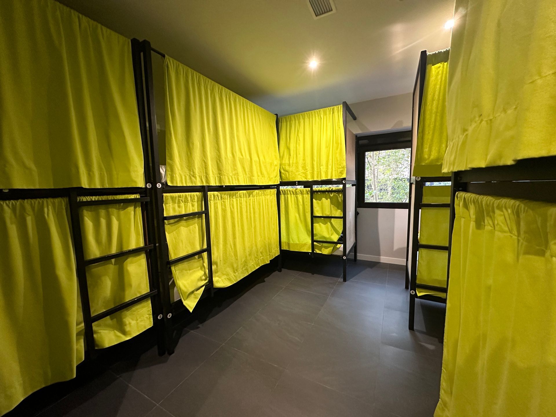 Literas con cortinas amarillas en una habitación de albergue.
