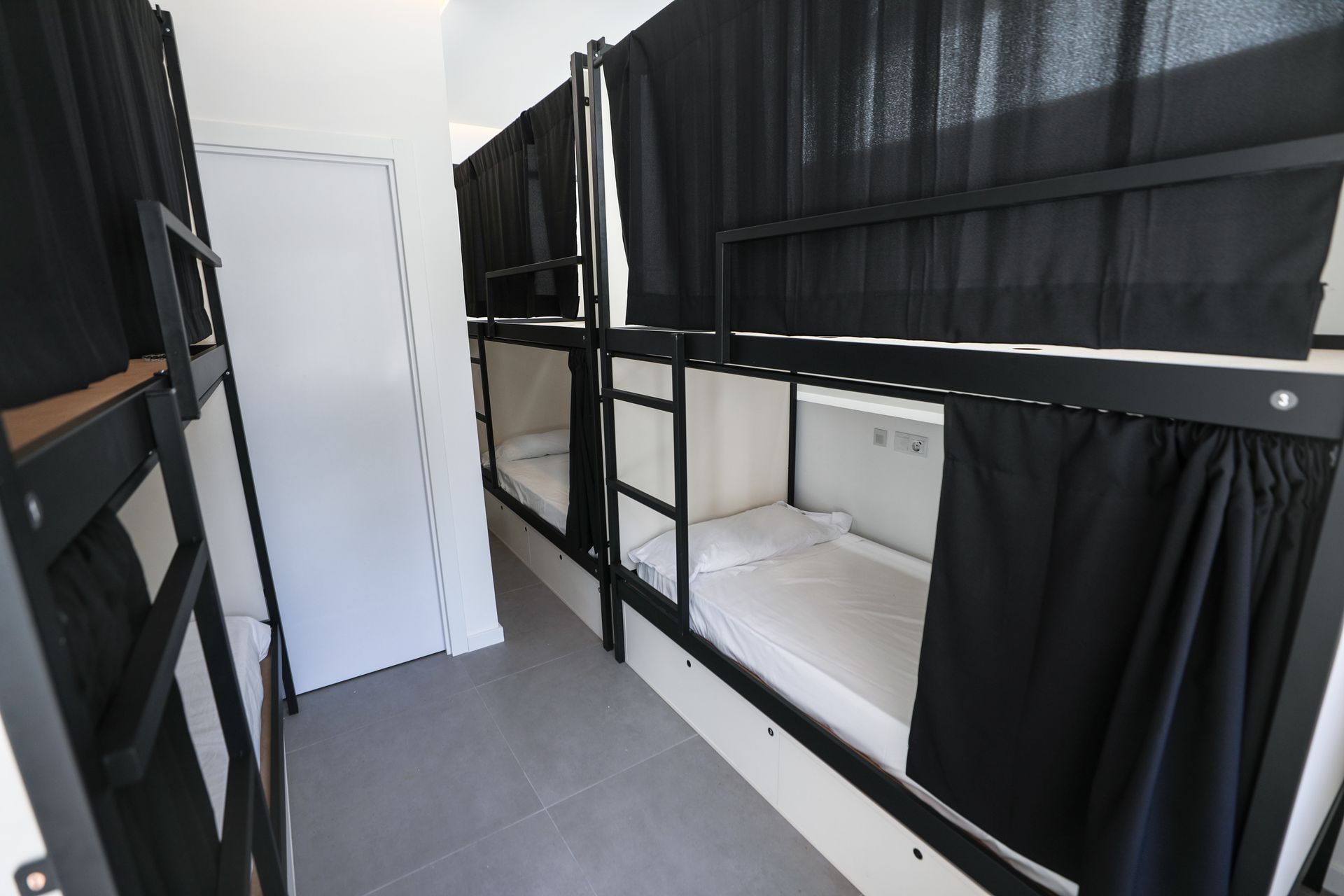 Una fila de literas con cortinas negras en una habitación.