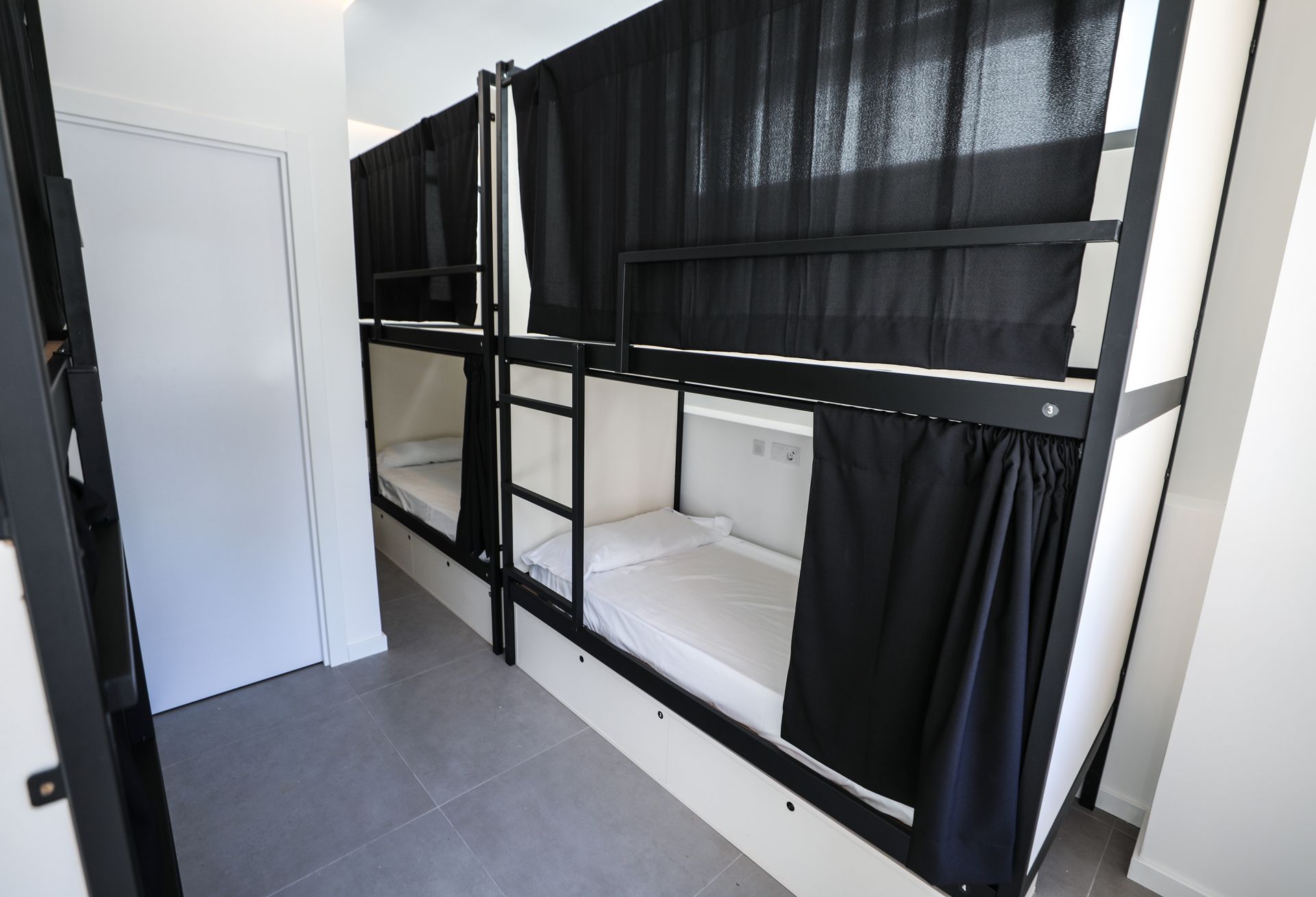 Una fila de literas con cortinas negras en una habitación.