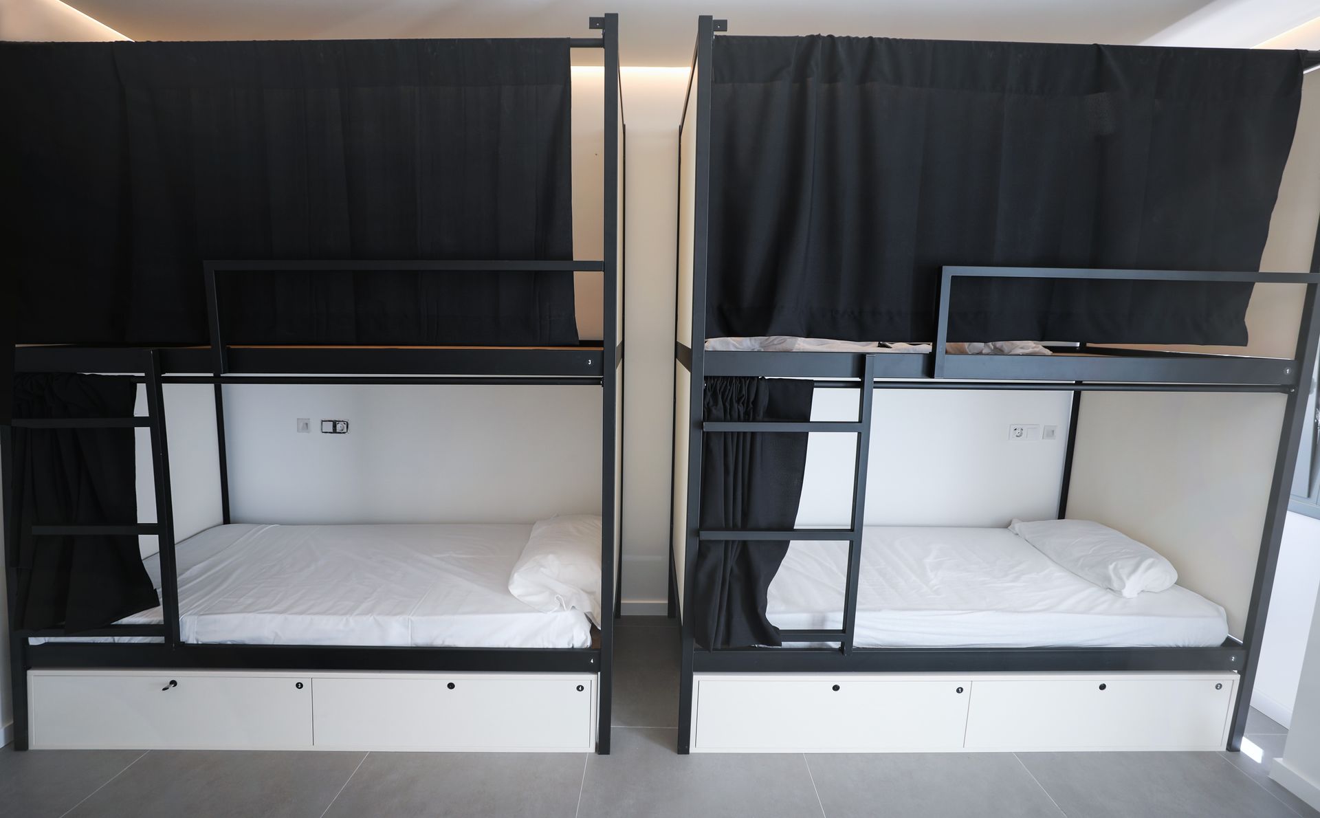 Cuatro literas con cortinas negras en una habitación.