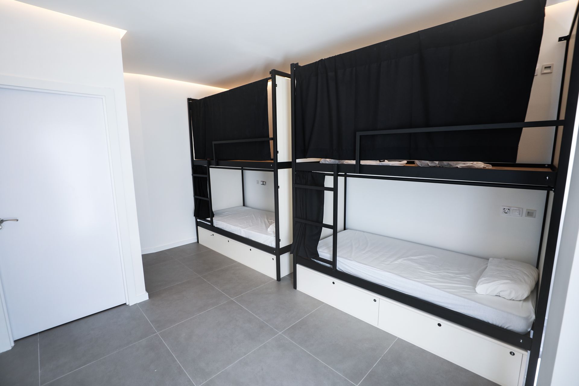 Una habitación con literas y cortinas negras en las paredes.