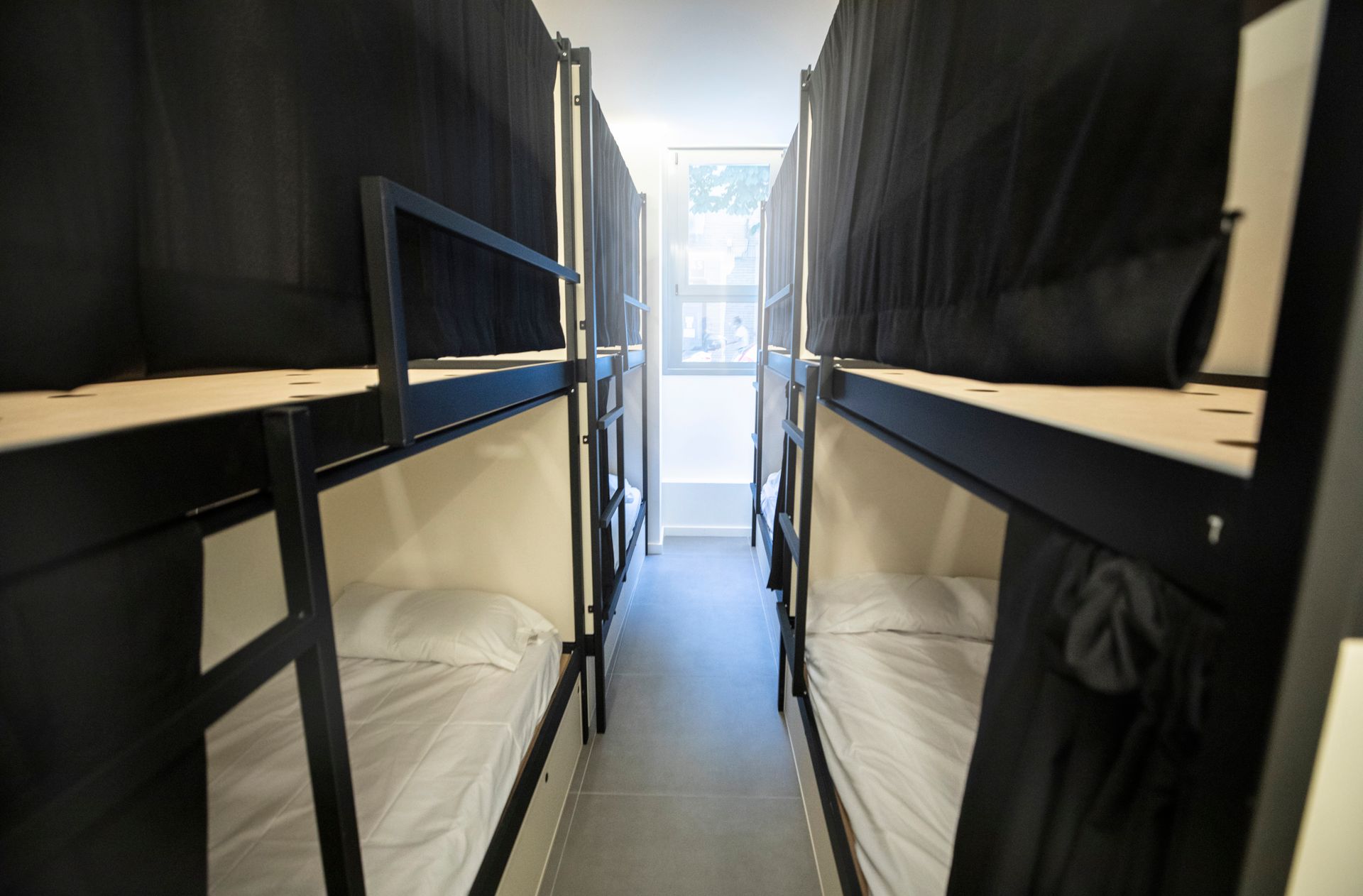 Una fila de literas en una habitación con cortinas negras.