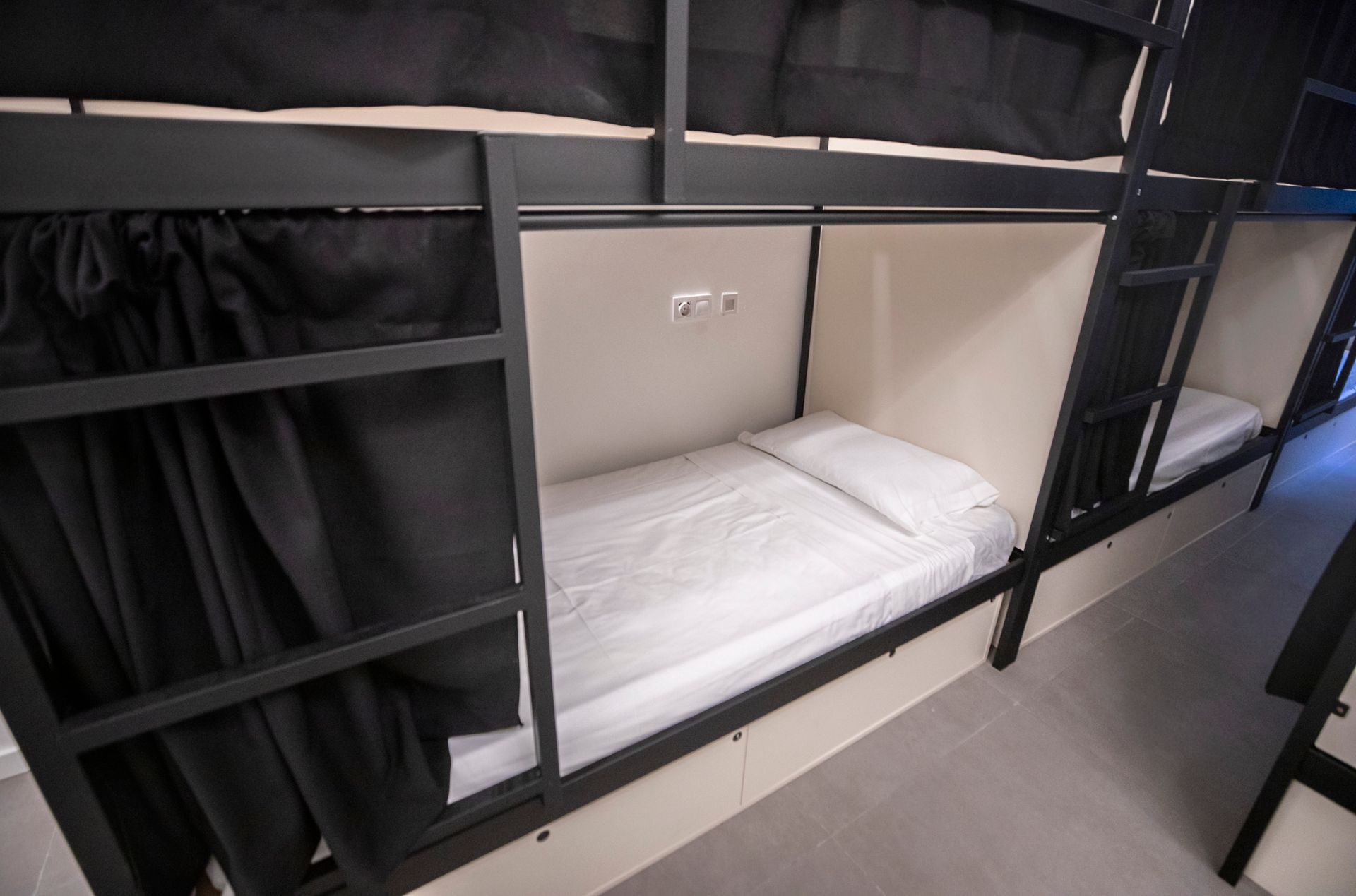 Una fila de literas con cortinas negras en un dormitorio.