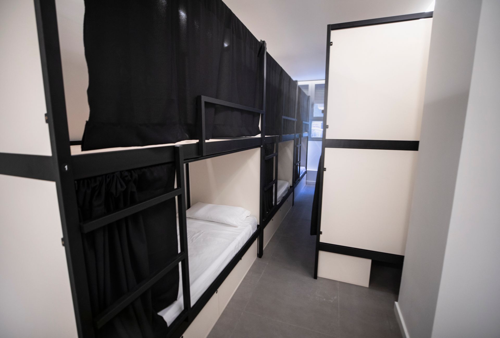 Una fila de literas en una habitación con cortinas negras.