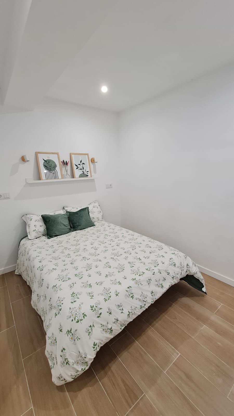 Una cama con un edredón blanco y almohadas verdes en un dormitorio.