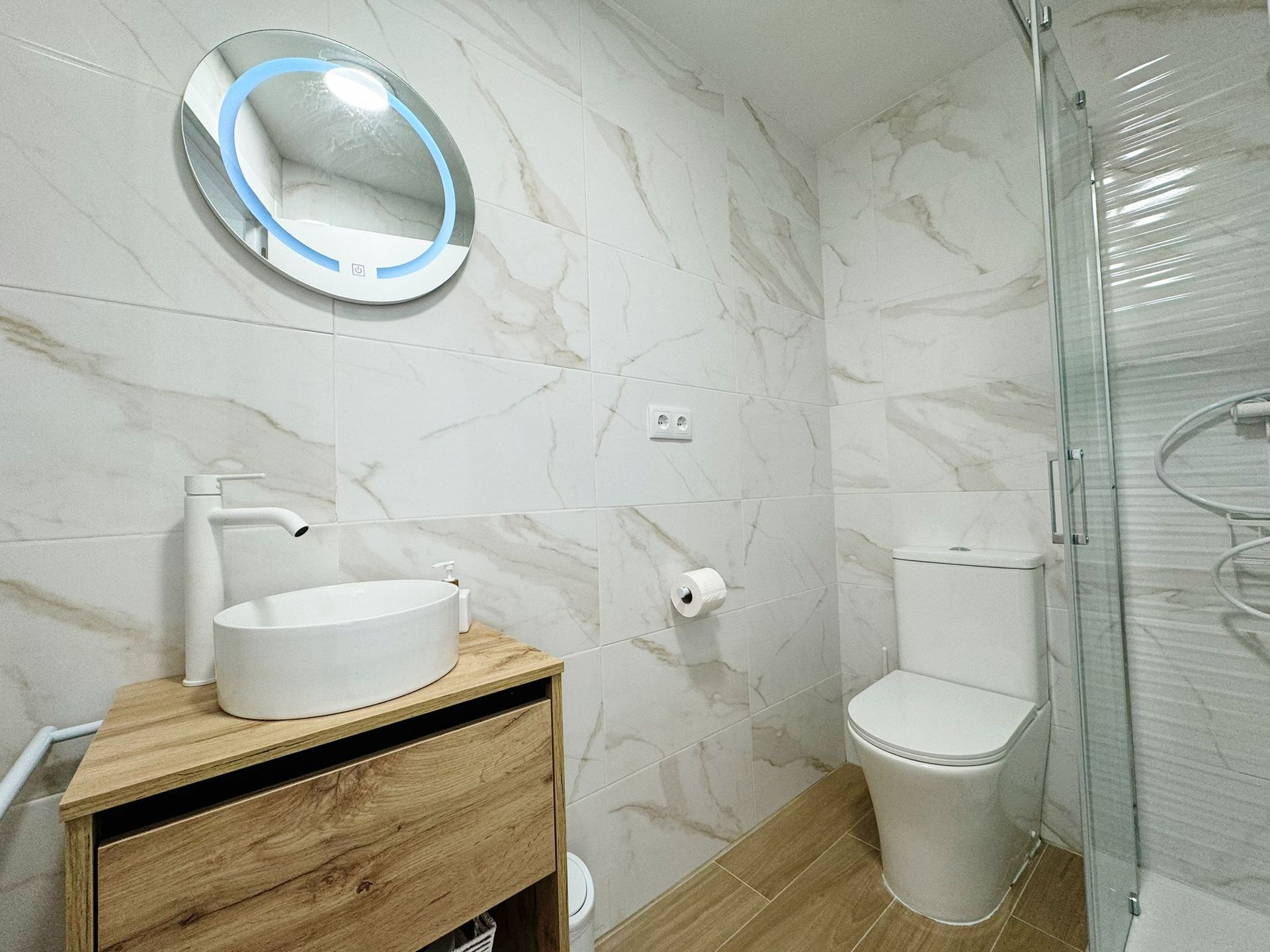 Un baño con inodoro, lavabo, espejo y ducha.