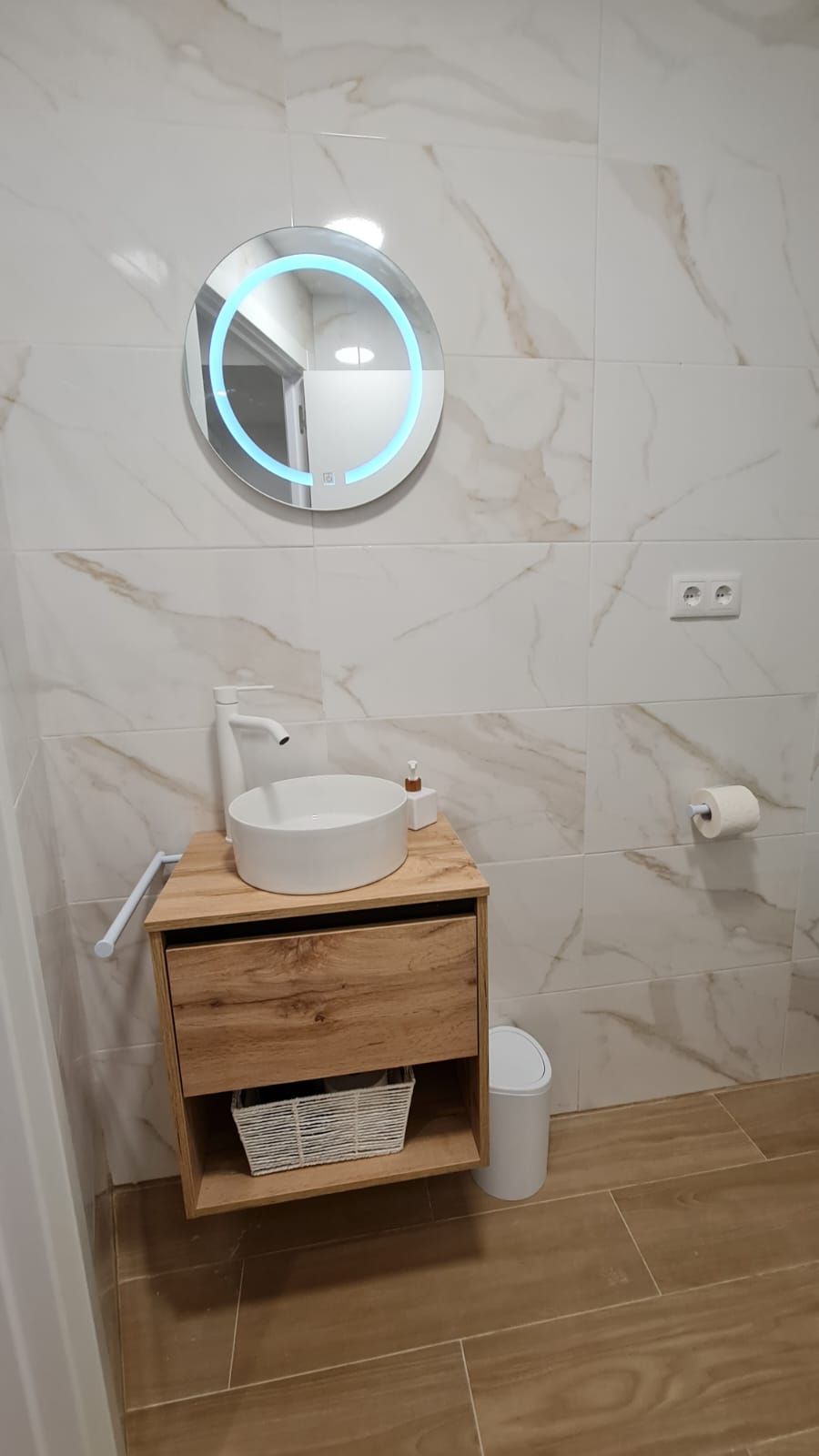 Un baño con lavabo, espejo y papelera.