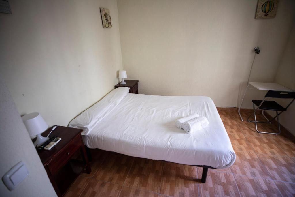 Un dormitorio con una cama, mesita de noche, escritorio y silla.